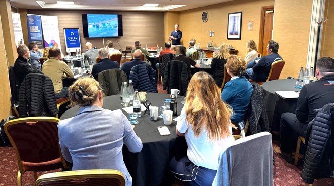 Business professionals attending a LEAD™ Masterclass in a conference room with presenter, Dan Hunt, former Director of Performance at British Cycling, standing at front near screen