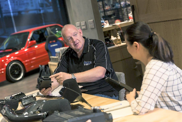 Pete Miles with an employee looking at car parts on a desk